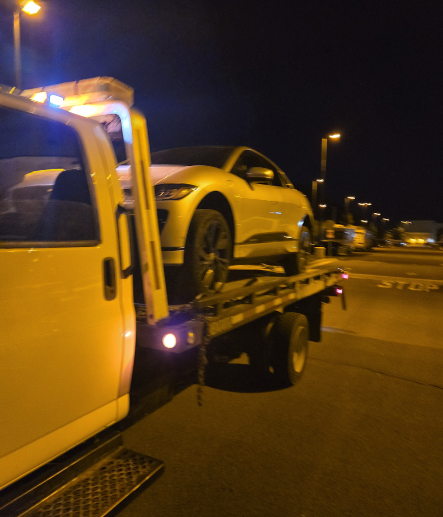 Baby Rocks Towing flatbed tow truck providing 24-hour emergency towing and vehicle recovery during a nighttime roadside assistance call.
